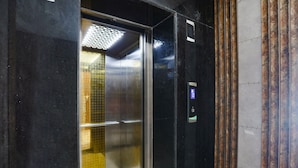 Un ascensor con interior metálico, un panel de control y una pared con diseño.