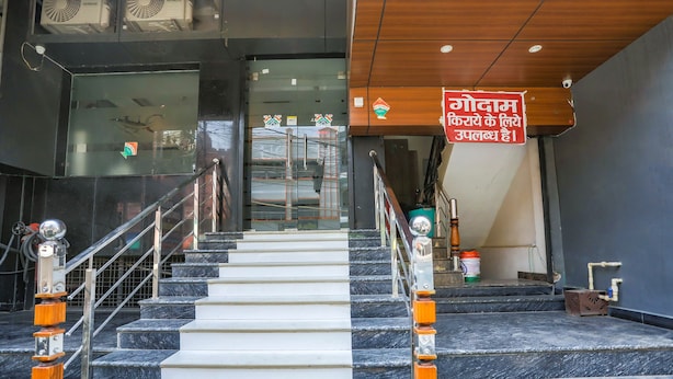 Una escalera con escalones de mármol y barandales de metal, que conduce a una puerta de cristal con un letrero en un idioma extranjero.