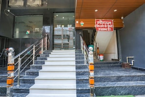 Eine Treppe mit Marmorstufen und Metallgeländern, die zu einer Glastür führt, an der ein Schild in einer fremden Sprache angebracht ist.