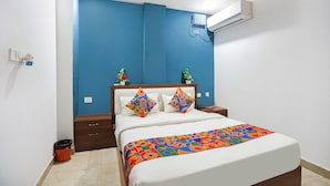 Un dormitorio con cama, mesita de noche, cubo de basura y aire acondicionado de pared.