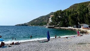 A beach with pebbles, a clear blue sky, and a few people. - Sehr Schöne und Moderne Ferienwohnung Lighthouse (Loutraki)