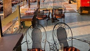 A seaside café with outdoor seating, a view of the sea and mountains, and a wooden fence. - Sehr Schöne und Moderne Ferienwohnung Lighthouse (Loutraki)