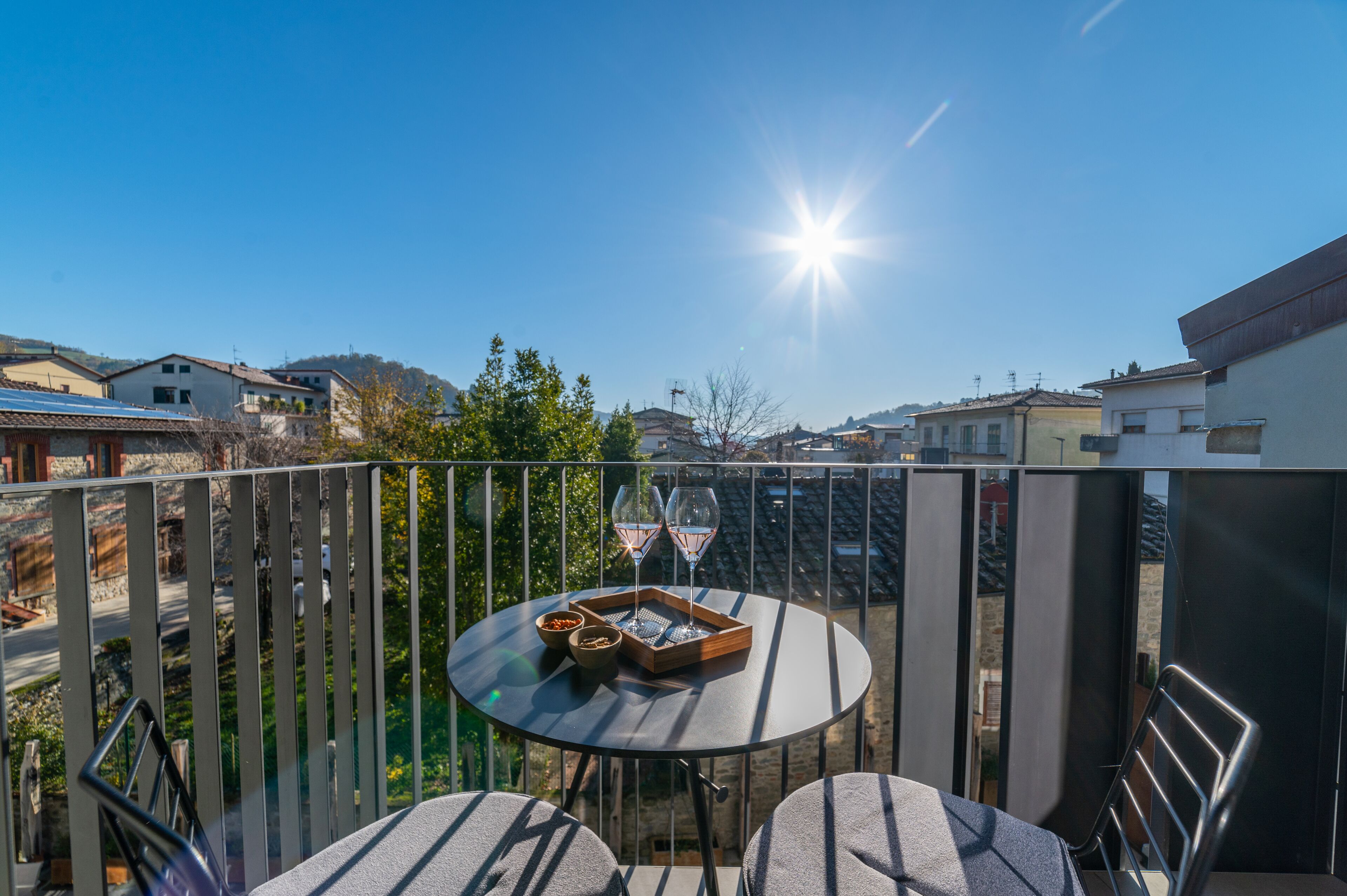 Un balcone con un tavolo rotondo, due sedie e un vassoio con bicchieri e snack.