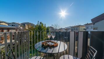 Un balcone con un tavolo rotondo, due sedie e un vassoio con bicchieri e snack.
