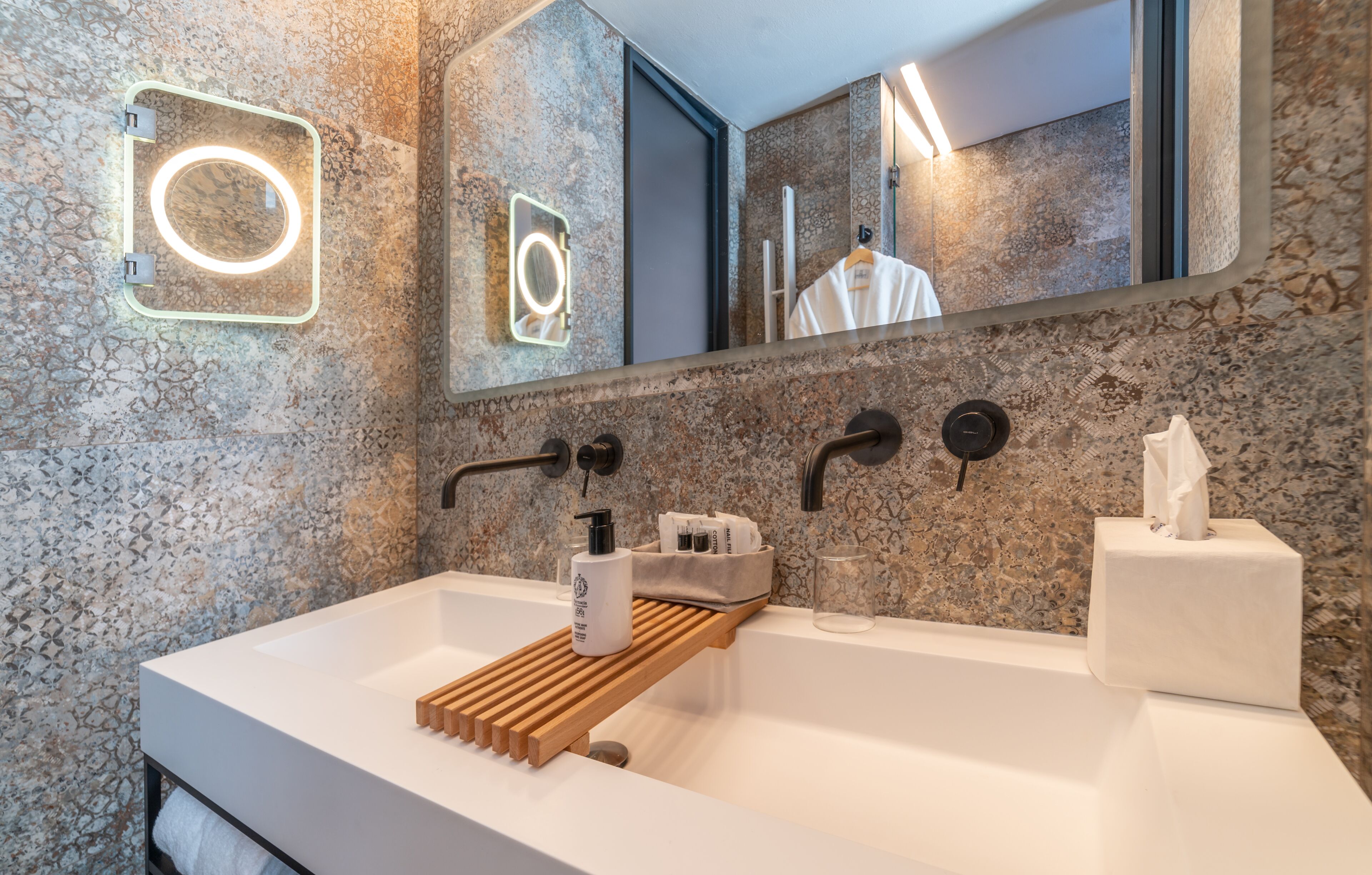 A modern bathroom with a large mirror, a built-in sink, and a wooden tray.