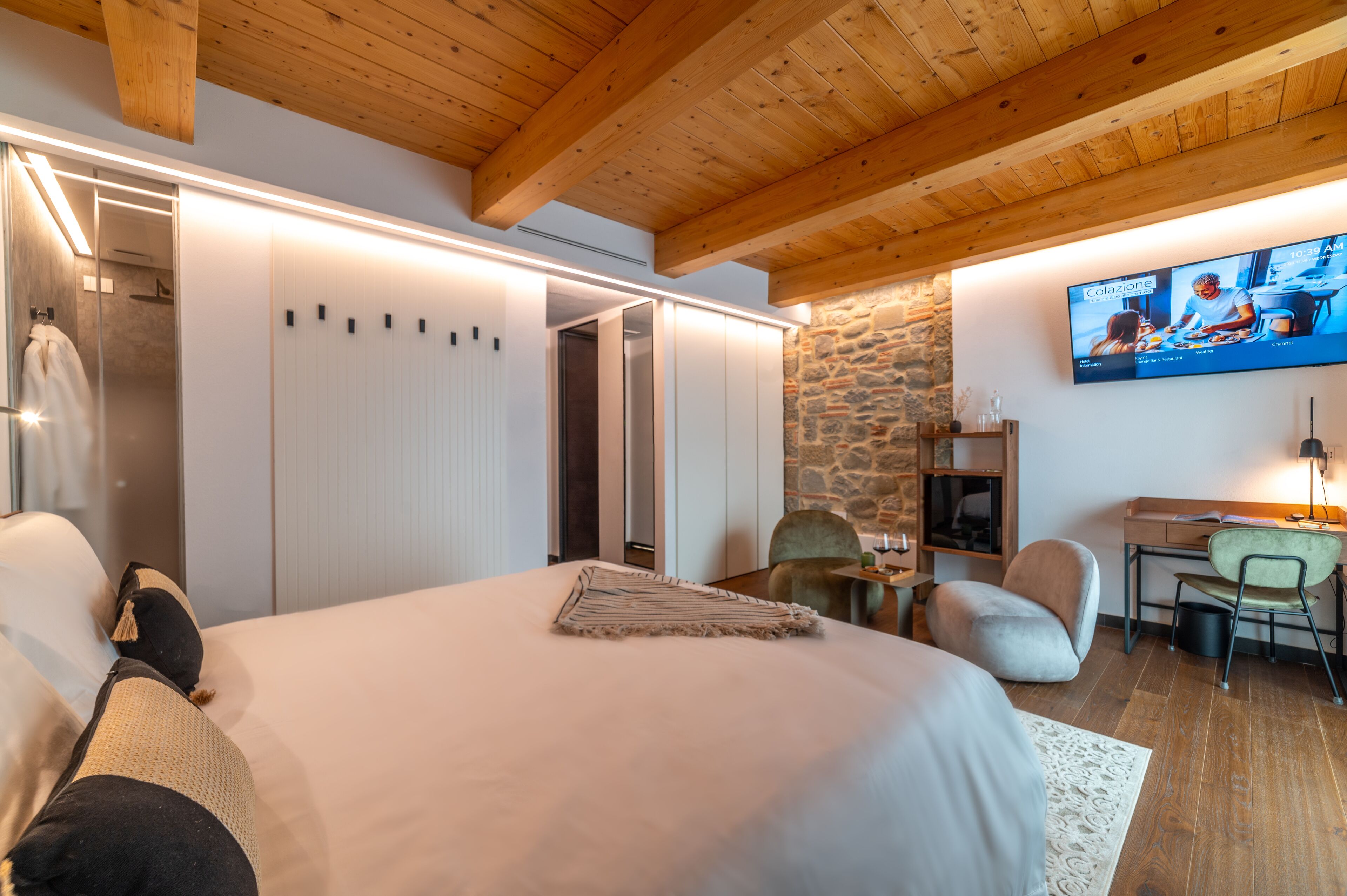 A modern hotel room with a large bed, a desk, and a television.