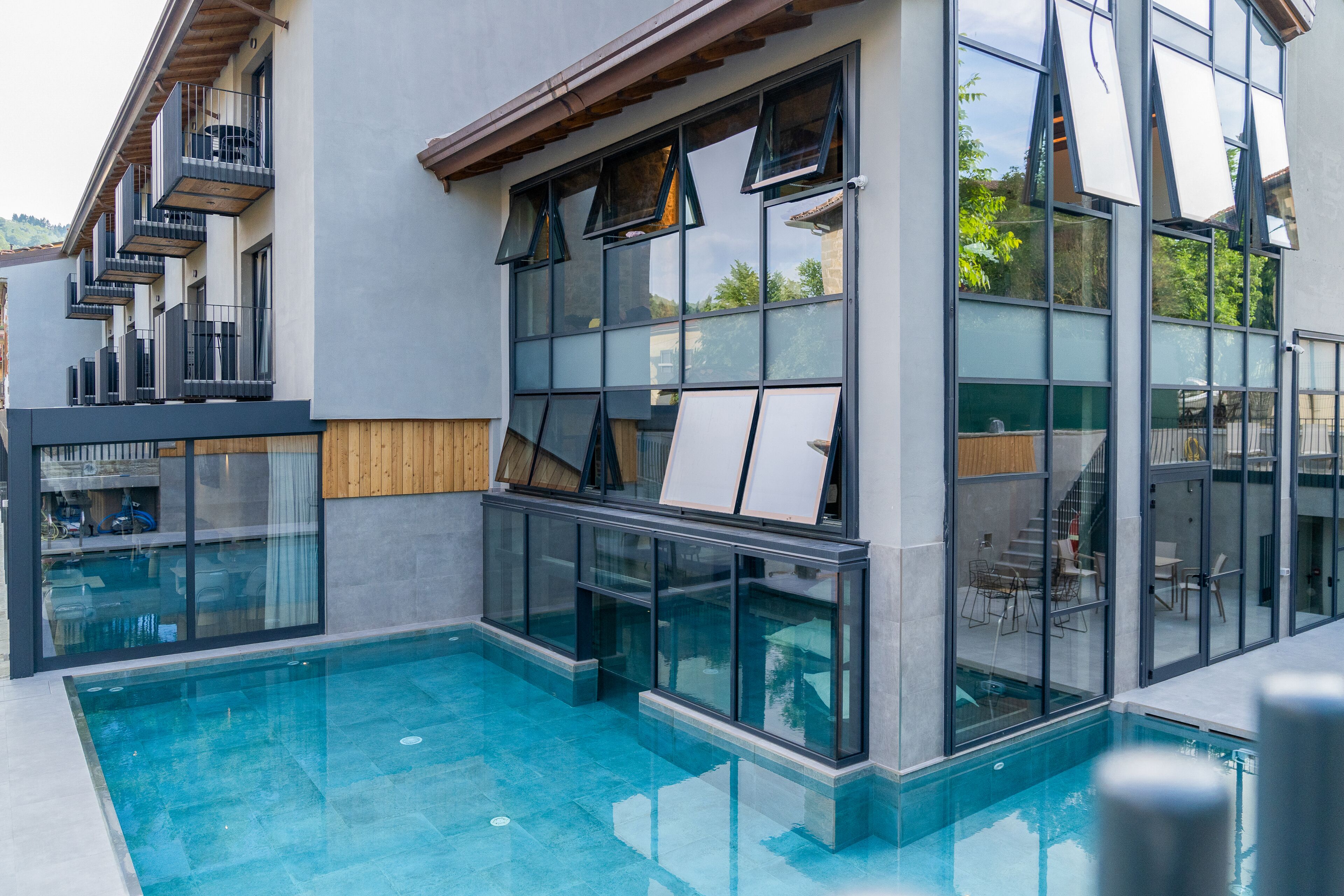 A modern building with a swimming pool, large windows, and balconies.