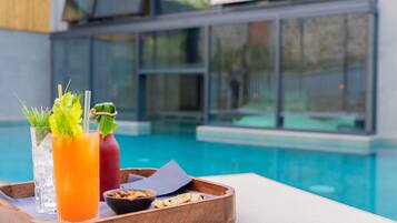 A tray with drinks and snacks by a poolside.