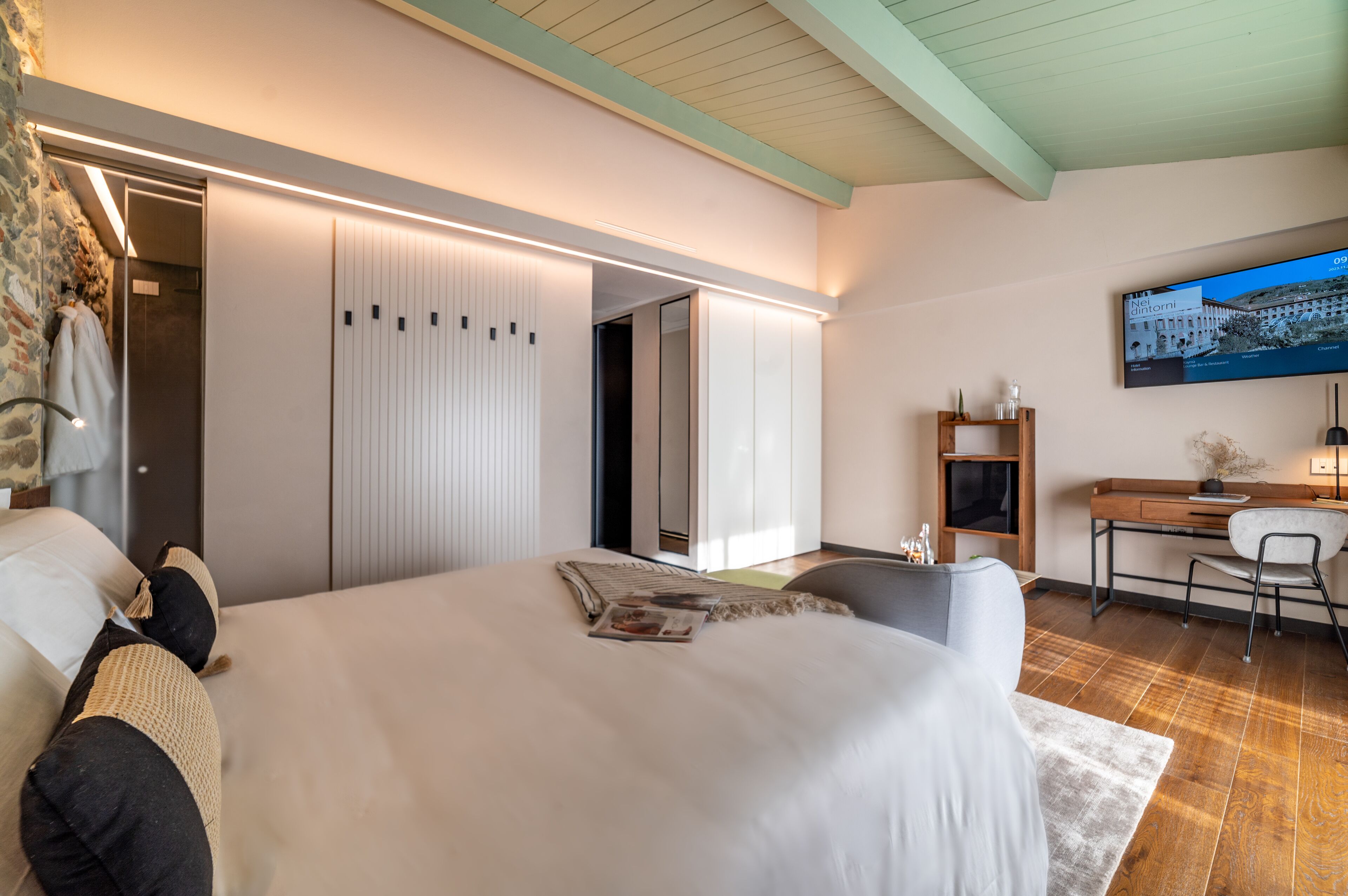 Ein modernes Schlafzimmer mit einem großen Bett, einem Schreibtisch und einem Fernseher.