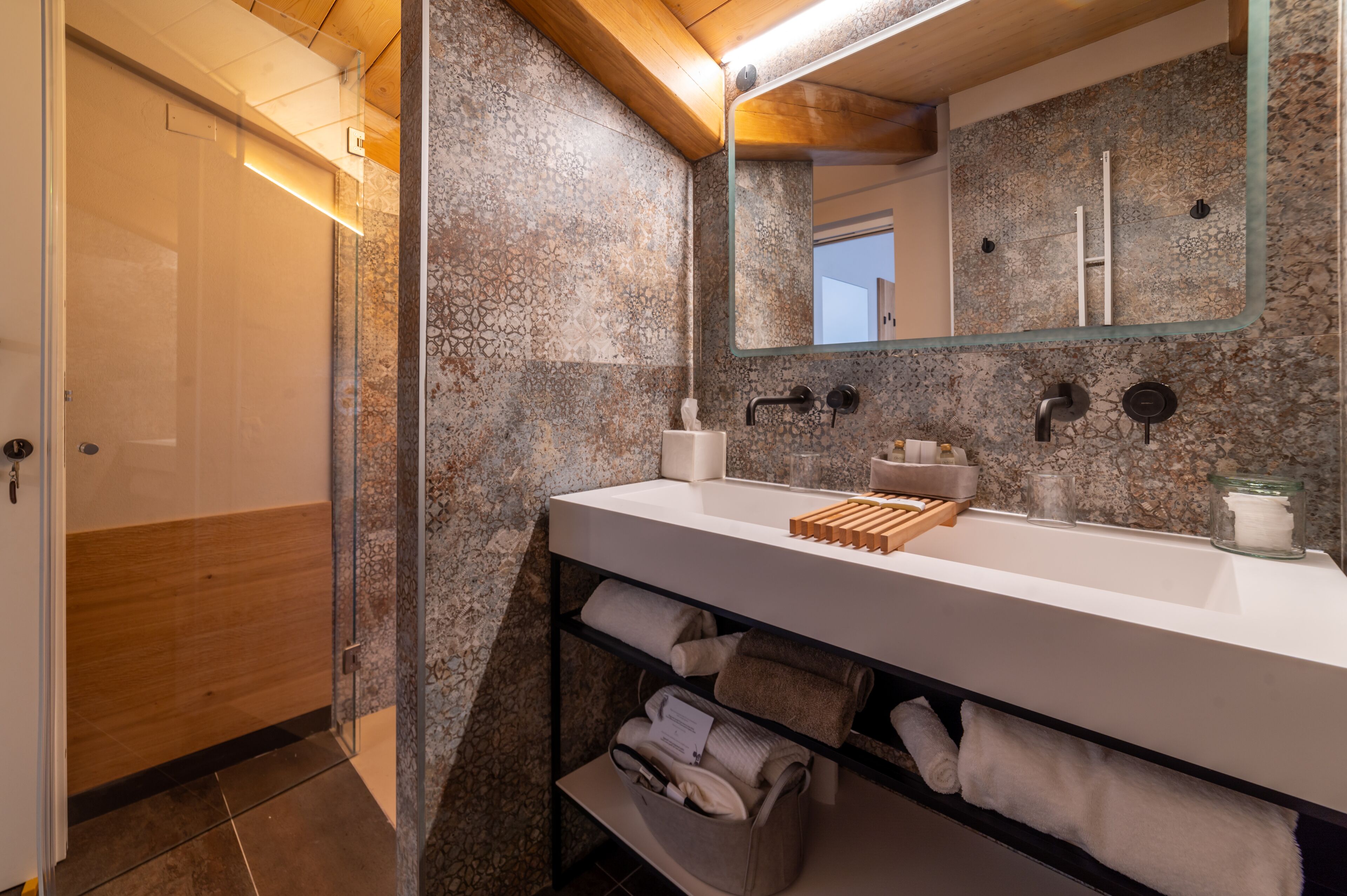 Een moderne badkamer met een granieten spatwand, een wit wastafelmeubel en een douchecabine met glazen wanden.