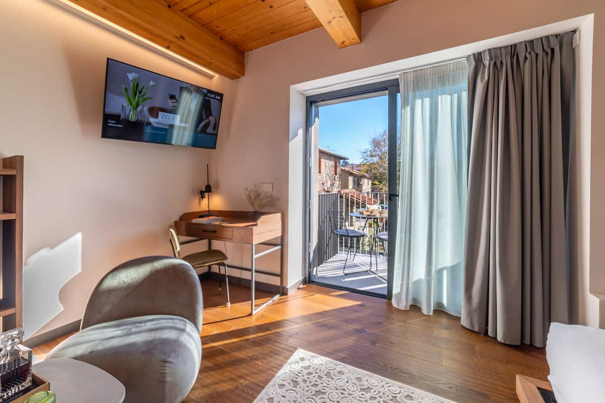 A modern living room with a wooden ceiling, a flat-screen TV mounted on the wall, a desk with a chair, and a sliding glass door leading to an outdoor area.