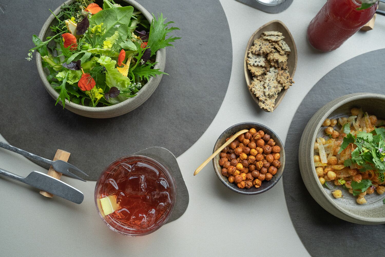 A table with a salad, chickpeas, a drink, and bread.