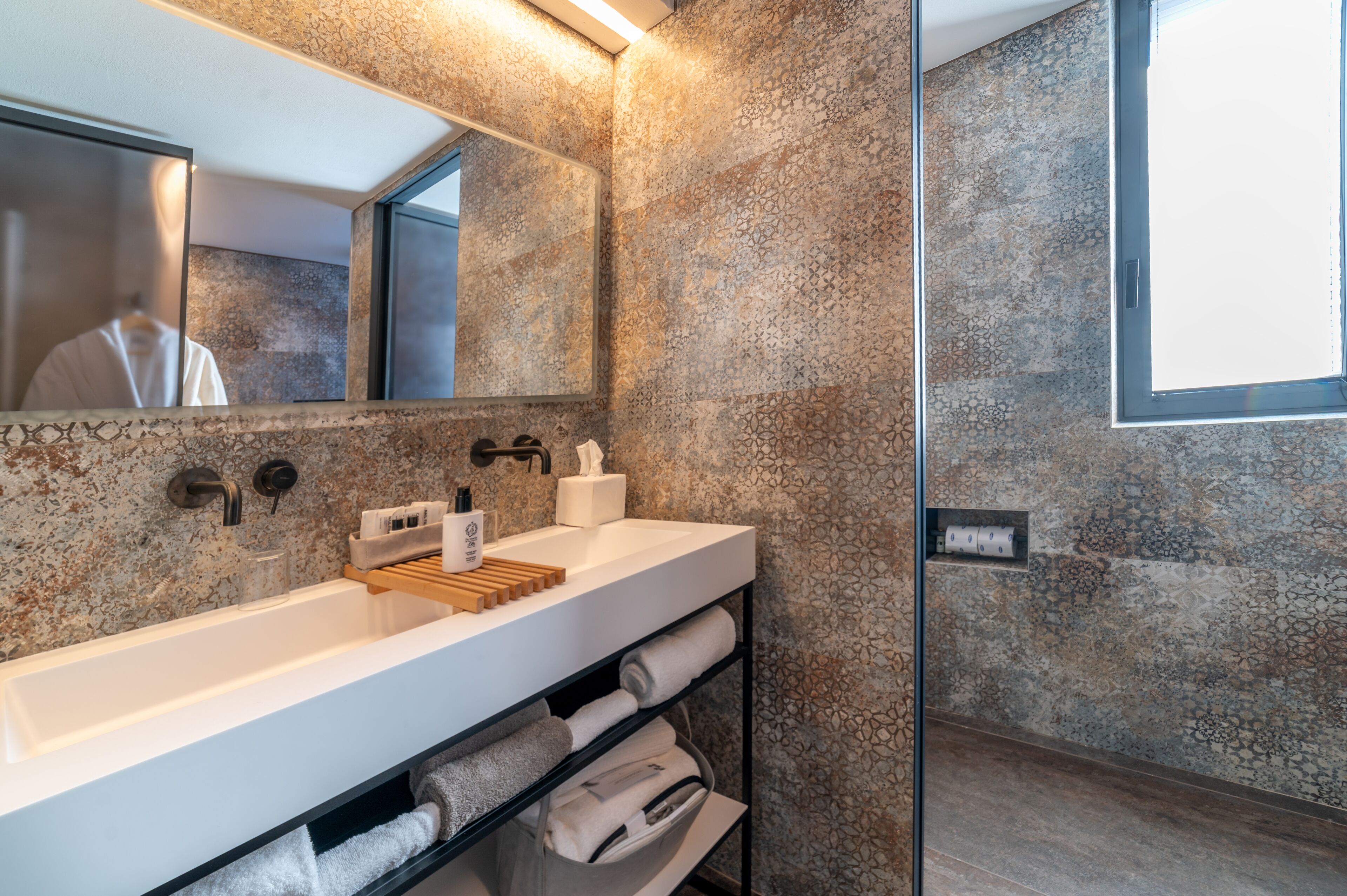 Un bagno moderno con un lavandino capiente, uno specchio e un porta asciugamani.