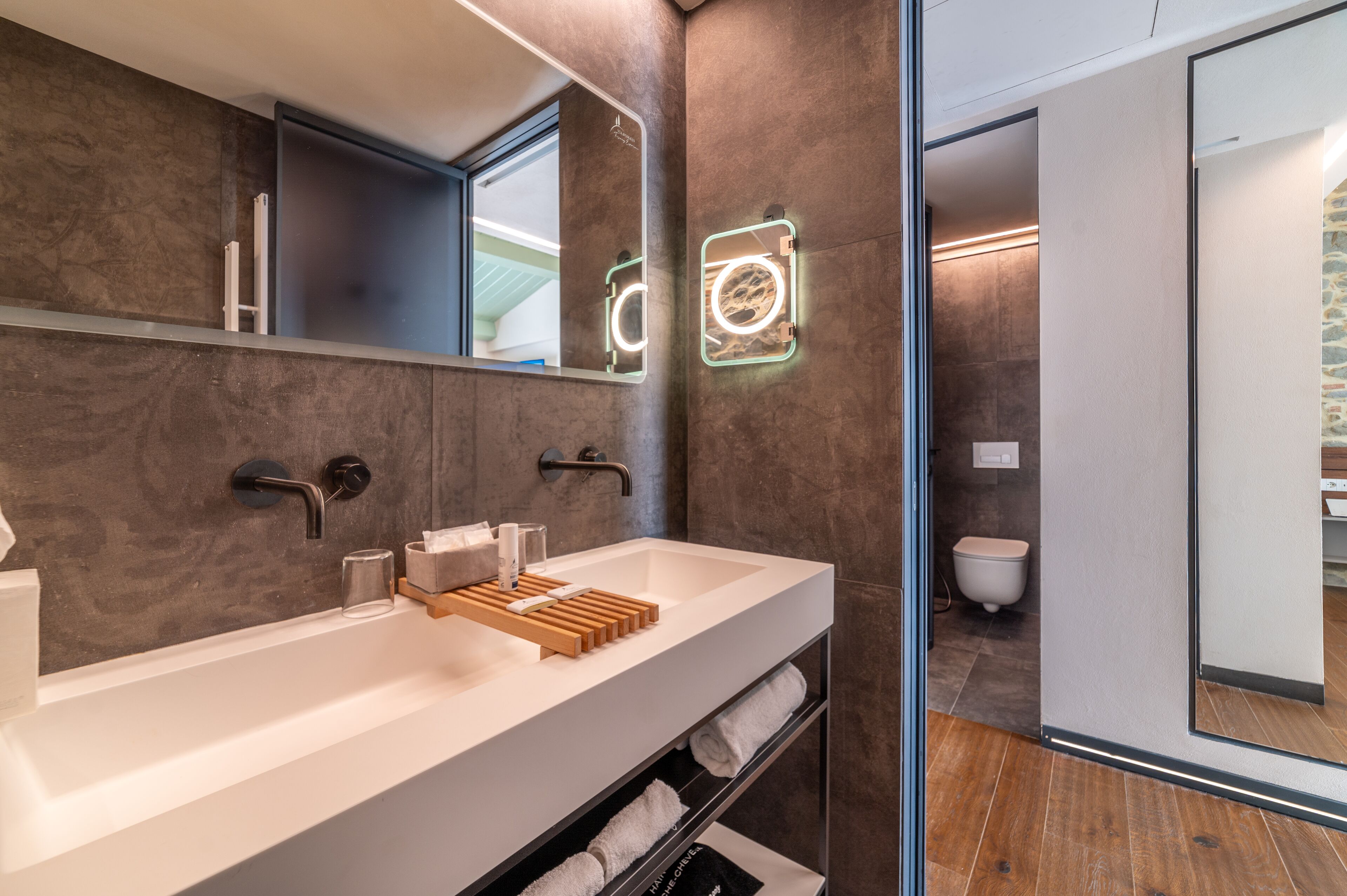 Un baño moderno con un lavamanos grande de color blanco, un toallero de madera y un espejo con iluminación.