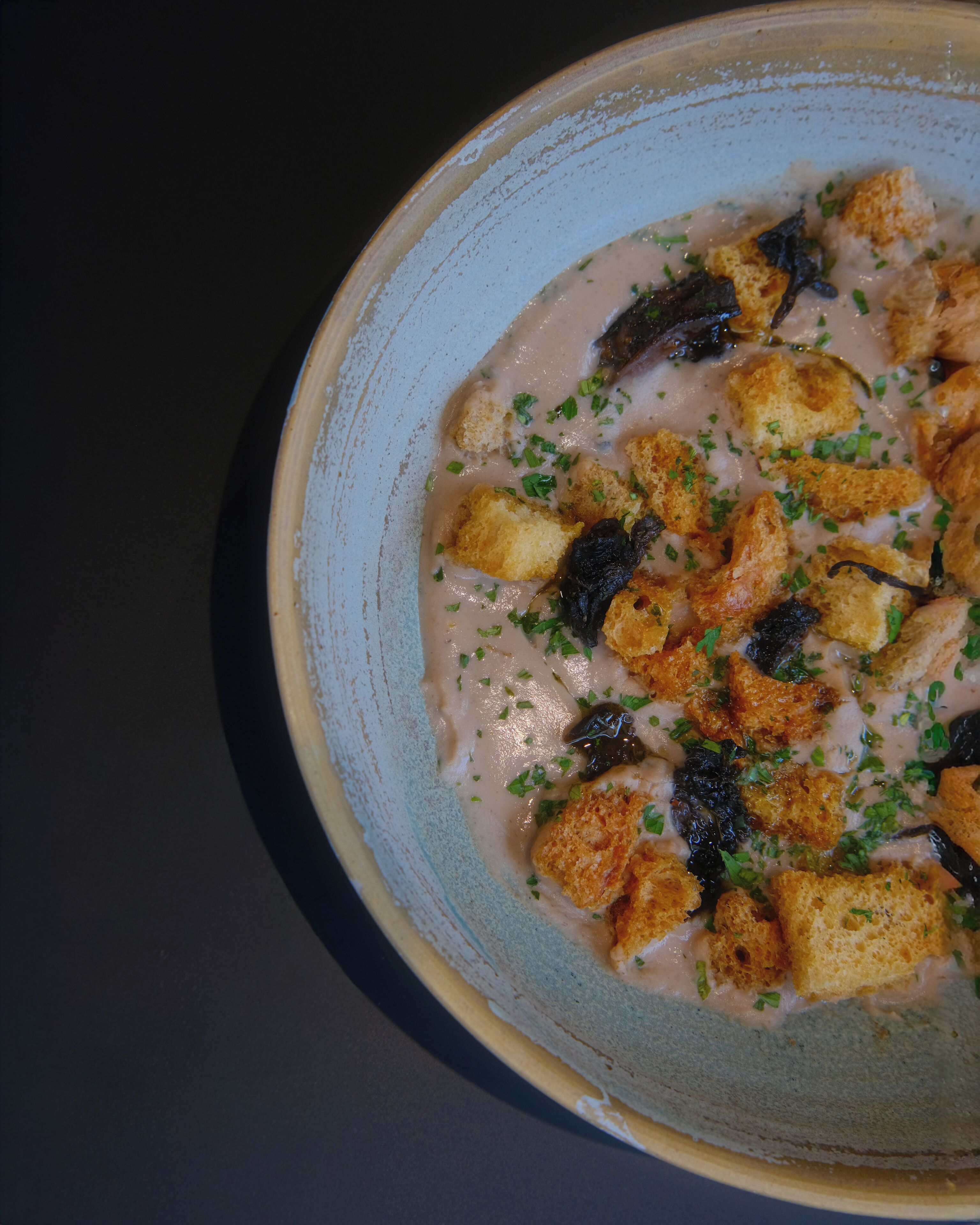 Un tazón de sopa con croutons y hierbas aromáticas.