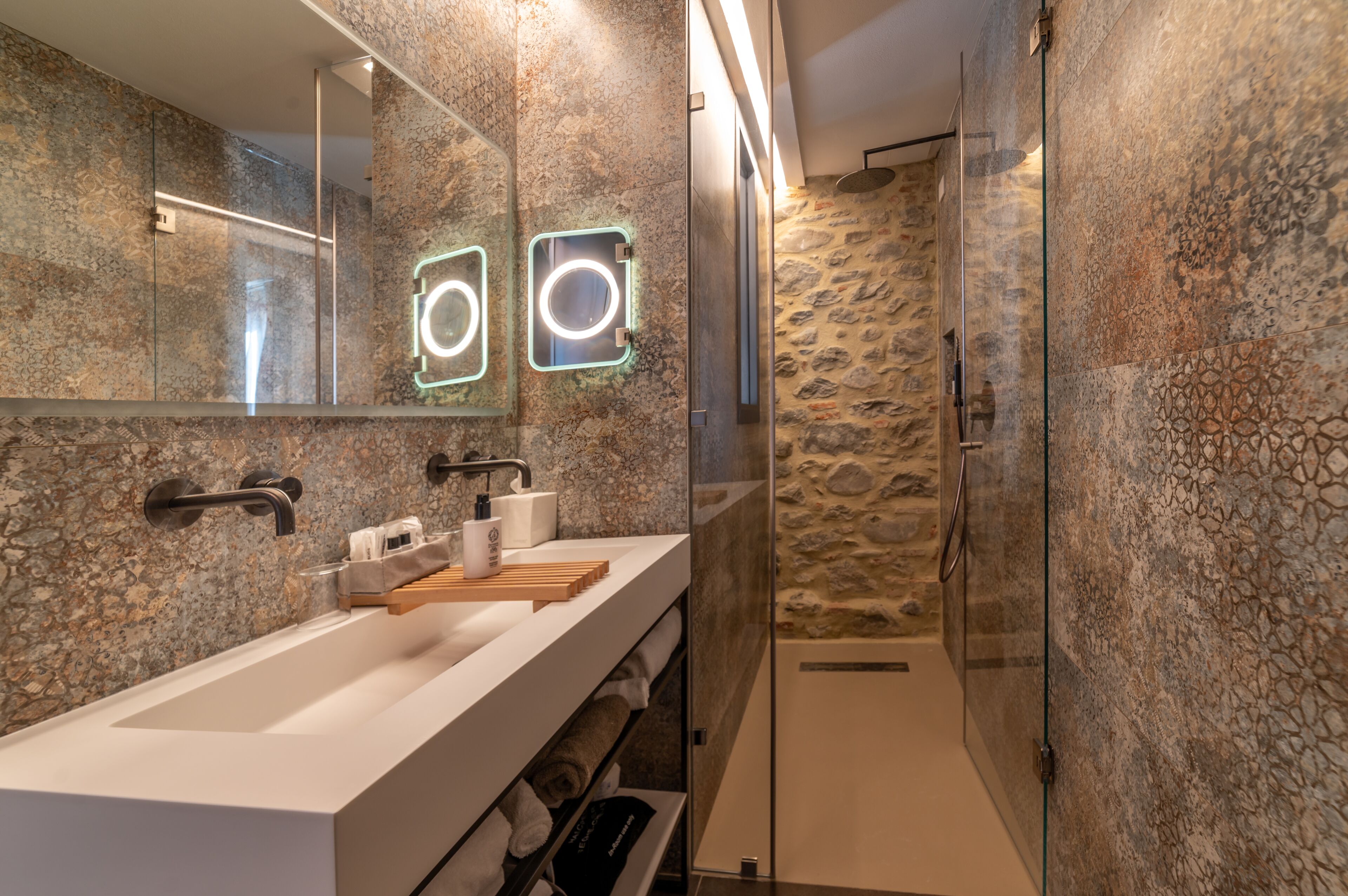 Un baño moderno con un espejo grande, dos lavamanos y una zona de ducha.