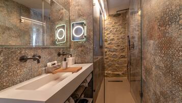 Un baño moderno con un espejo grande, dos lavamanos y una zona de ducha.