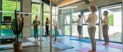A modern yoga studio with glass walls, wooden floors, and a cactus plant.