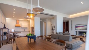 A modern living room with a wooden dining table, grey sofa, and a fireplace.