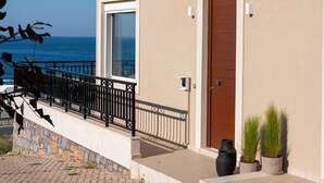 A modern building with a balcony, a wooden door, and potted plants.