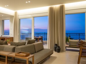 Ein großzügiger Wohnbereich mit einer großen Couch, einem Holztisch und einem Balkon mit Meerblick.