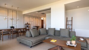 A modern living room with a sectional sofa, wooden coffee table, and dining area with chairs and a table.