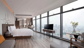 A modern hotel room with a large bed, a TV, a small table, and a city view through large windows. - UrCove by Hyatt Shenzhen Bay Futian Port (Shenzhen)