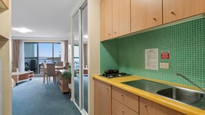 A kitchen with a green tiled backsplash, wooden cabinets, a yellow countertop, and a view to the outside.