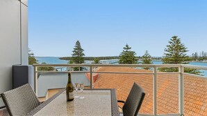 A balcony with a table, chairs, and a bottle of wine.