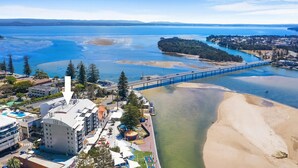 A coastal area with a bridge, beach, and buildings with balconies.