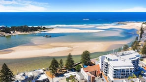 A coastal area with clear waters, sandy beaches, and buildings with balconies overlooking the sea.
