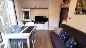 Une cuisine moderne avec des meubles blancs, un plan de travail noir et un téléviseur encastré.
