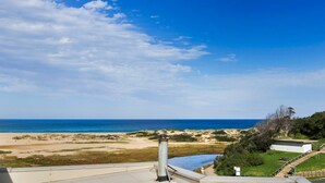 Vista costera desde un balcón con vista a la playa y el océano.
