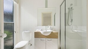 Ein modernes Badezimmer mit Toilette, Waschbecken und Dusche.