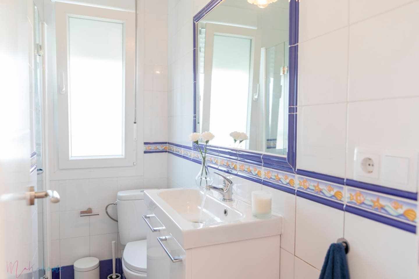 A bathroom with a white sink, a mirror, and a toilet.