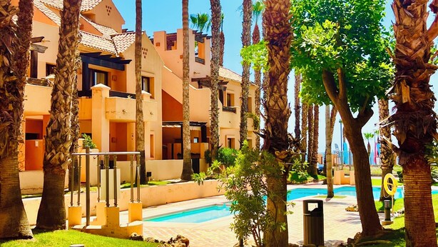A resort with a pool, palm trees, and a pathway leading to the pool.