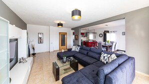 Una sala moderna con un sofá modular, una mesa de centro de vidrio y un televisor.