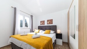 Un dormitorio con cama, mesitas de noche, una ventana y obras de arte en la pared.