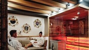 Een modern interieur met een sauna met glazen wanden, een houten plafond en decoratieve spiegelwanden.