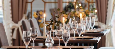 A dining area with tables set for a meal, featuring clear glassware and candles.