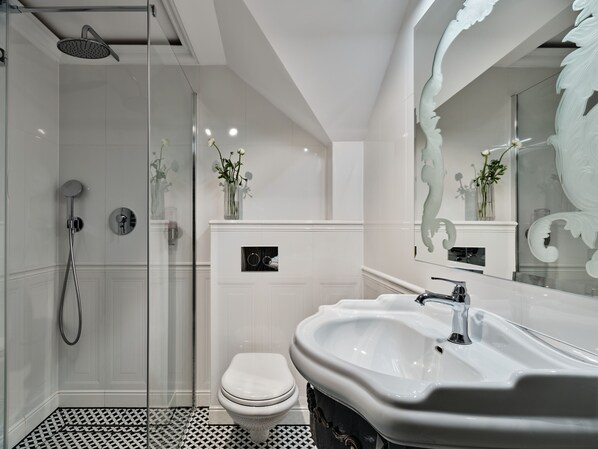 A modern bathroom with a glass-enclosed shower, a white toilet, and a large sink with a mirror.