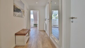 Un pasillo con un banco, un espejo grande y una puerta que da a una habitación.
