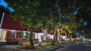 Una hilera de edificios hoteleros con tejados rojos, rodeados de árboles y senderos bien iluminados.