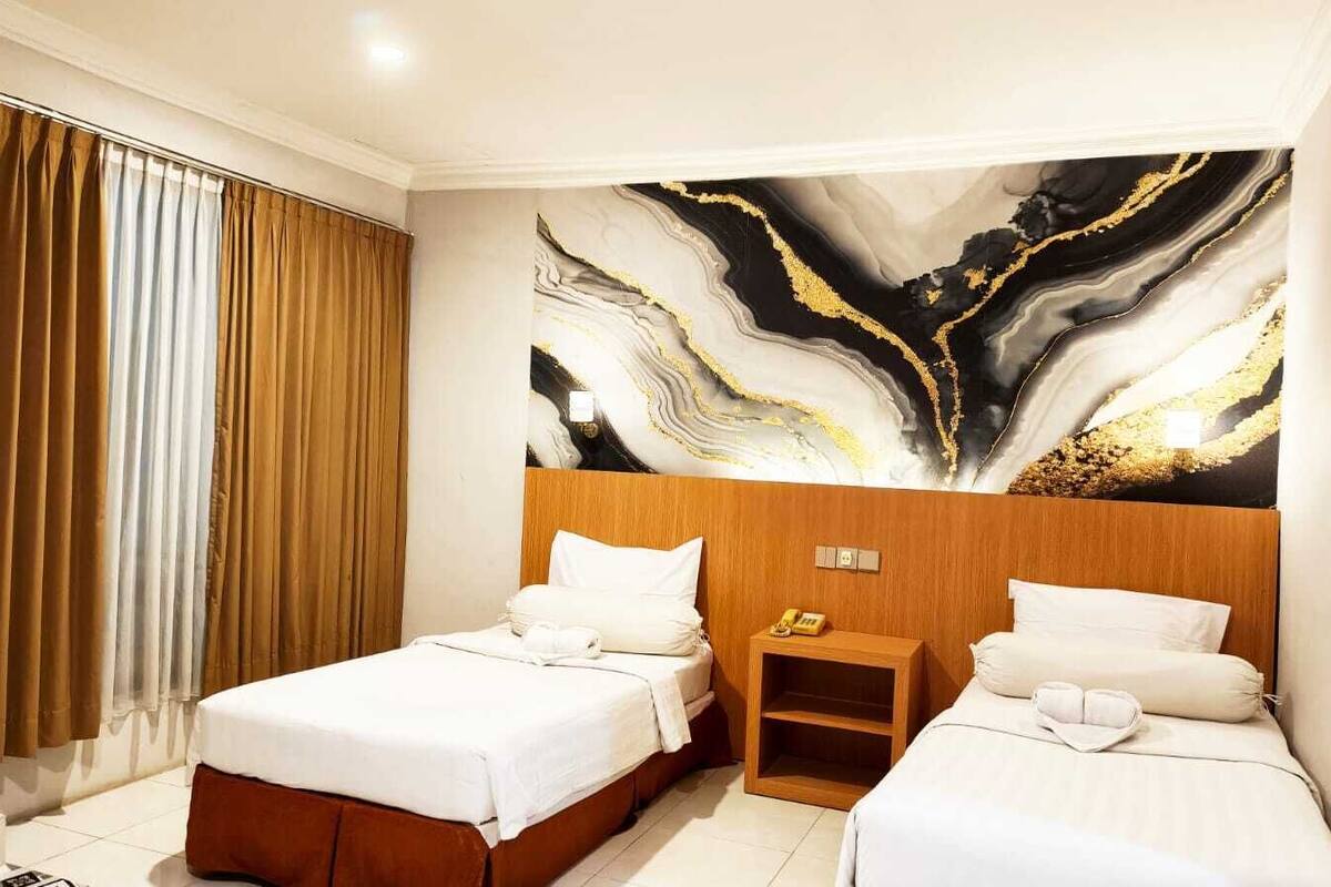 A hotel room with two beds, a wooden headboard, a nightstand, and a marble wall art.