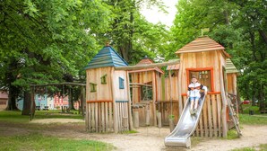 Un parque infantil con estructuras de madera, incluyendo un tobogán y zonas de escalada.