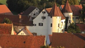 Un pueblo europeo tradicional con una torre blanca destacada y edificios de tejados rojos.