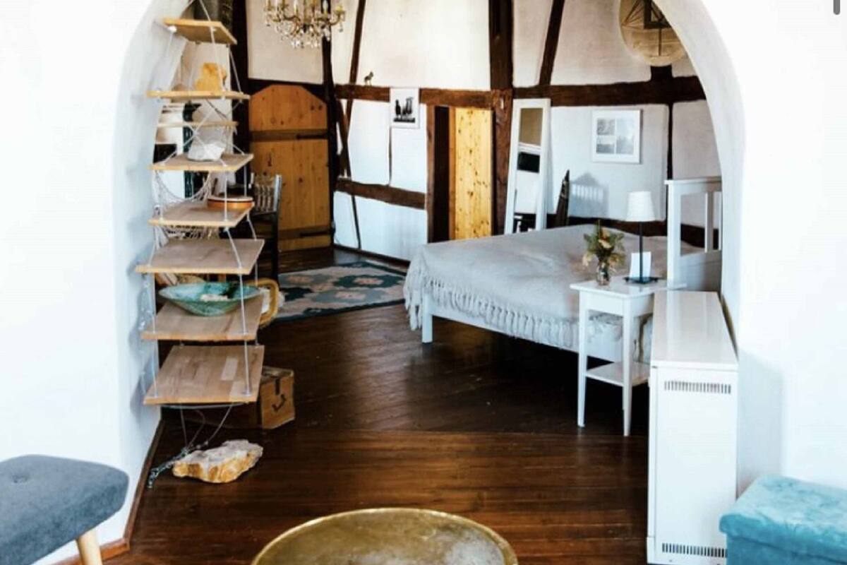 Una habitación con una cama, un escritorio blanco, una estantería y un candelabro.