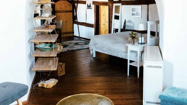 Una habitación con una cama, un escritorio blanco, una estantería y un candelabro.