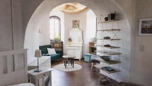 Una habitación acogedora con suelo de madera, un sofá verde, un armario blanco y una estantería.