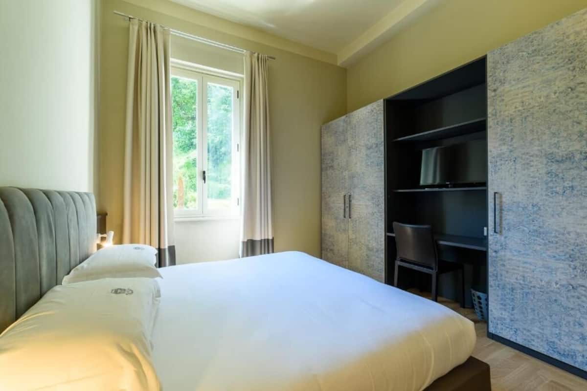 A bedroom with a bed, a desk, and a wardrobe.